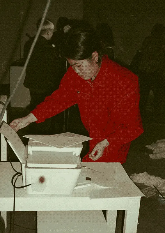 Hikari Nishida standing over her printer feeding it fresh paper.