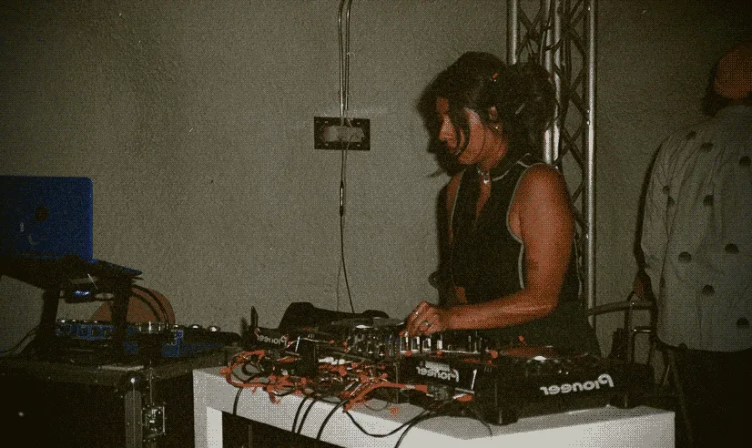 Gladys Camilo standing over a dj booth adjusting the sound.
