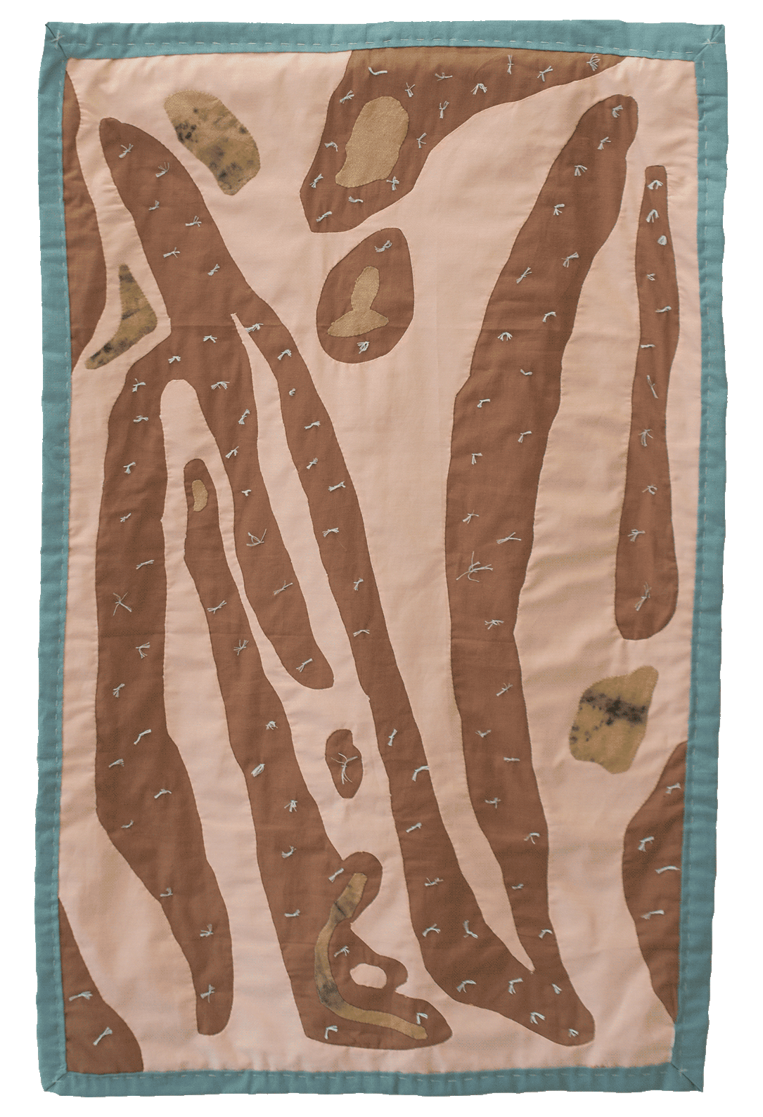 A peach colored quilt with brown organic shapes are scattered throughout 
                the surface of the quilt along with white knots. The quilt has a light blue binding.