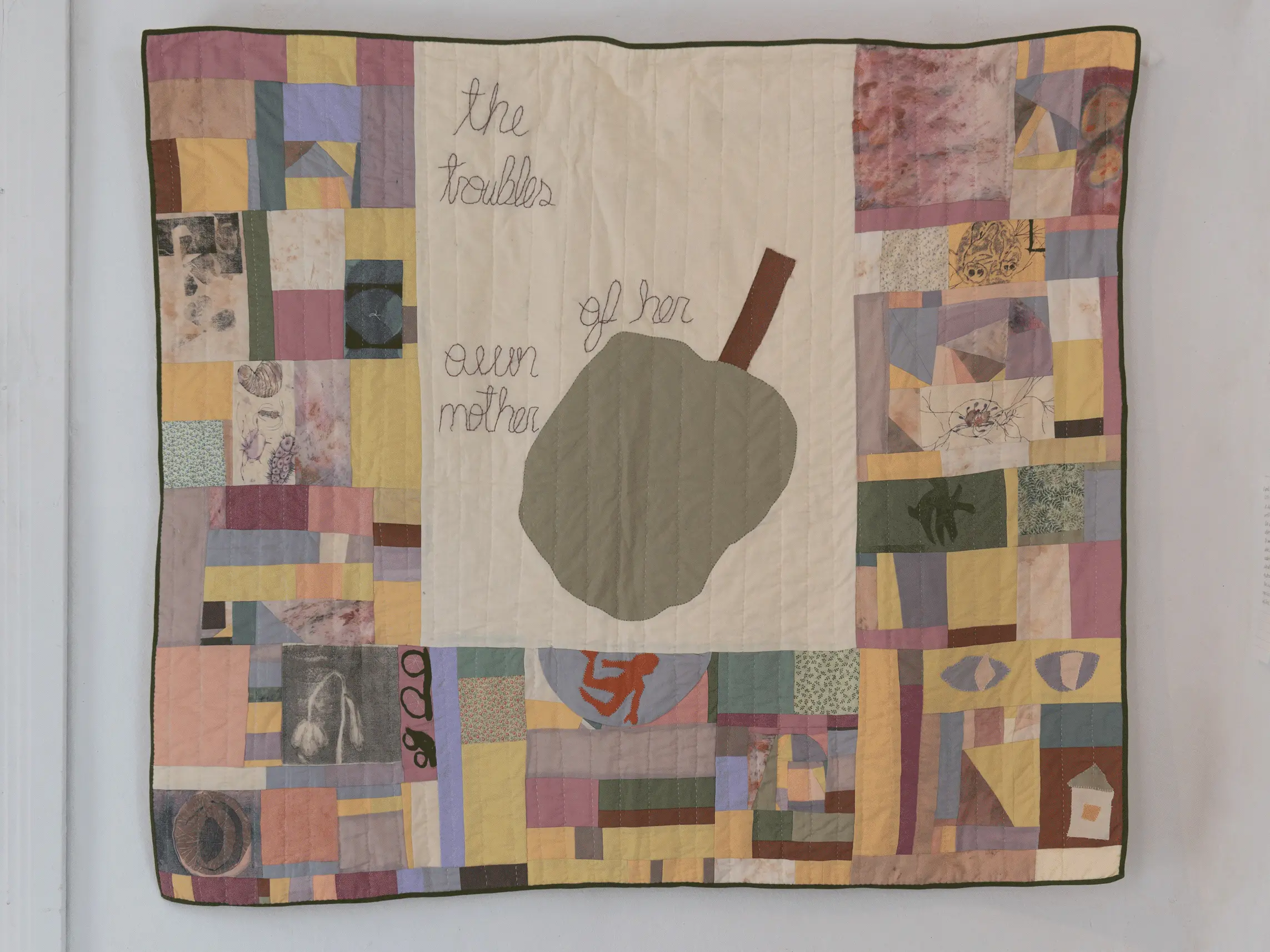 A close up of the quilt with the apple and small text that reads: 
                    The troubles of her own mother