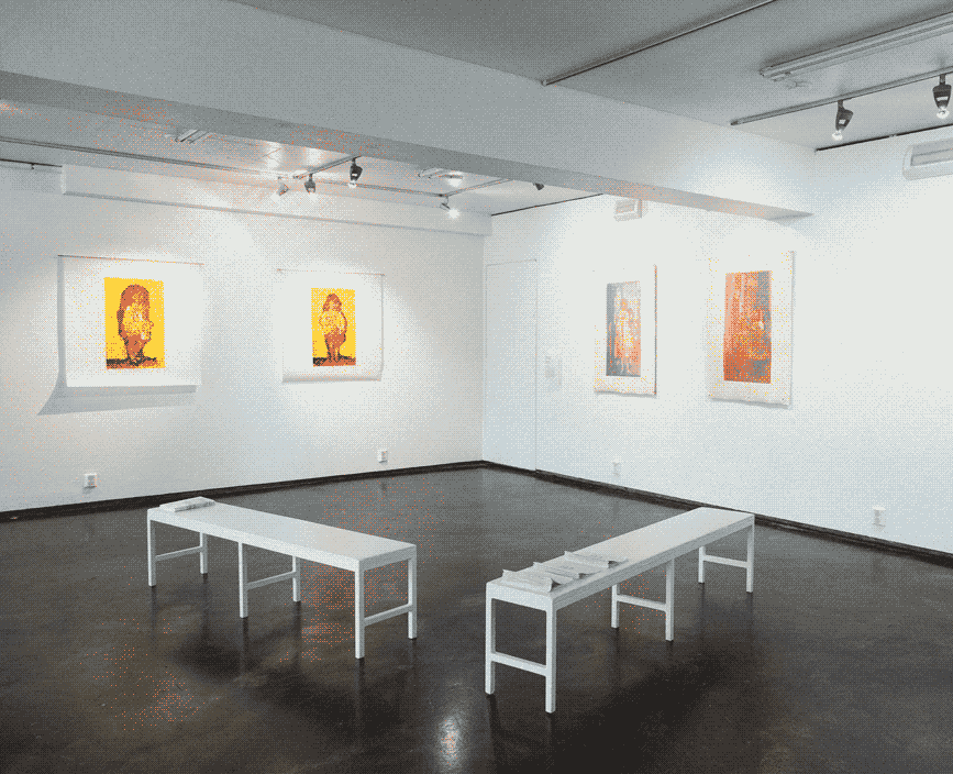 Two white walls in an exhibition space white benches in the middle of the room.
                On the left wall hang two silk-screen prints of a child made with red, black and yellow ink.
                on the right wall are two other silk-screen prints of another child made with blue and 
                red inks.
